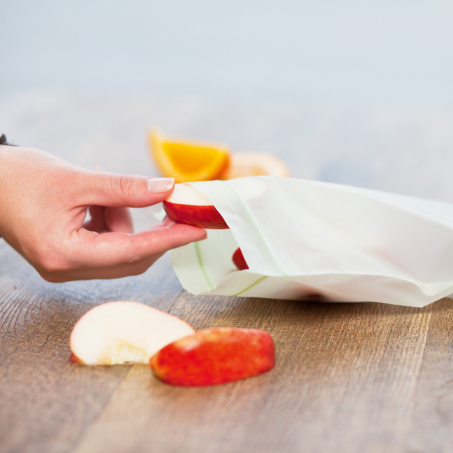 Person using a BioBag resealable food storage bag to store slices of apple, showing the resealable opening