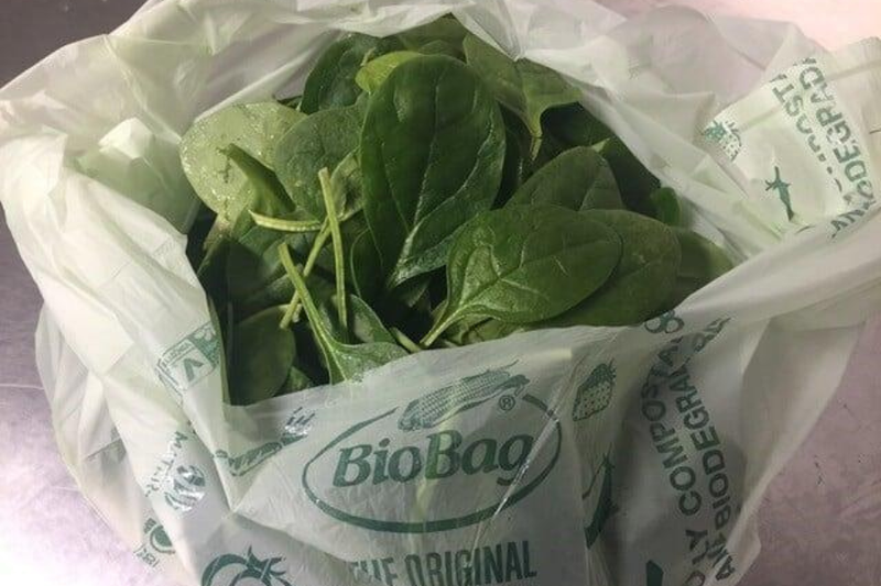 Photo of a compostable liner filled with fresh spinach. 