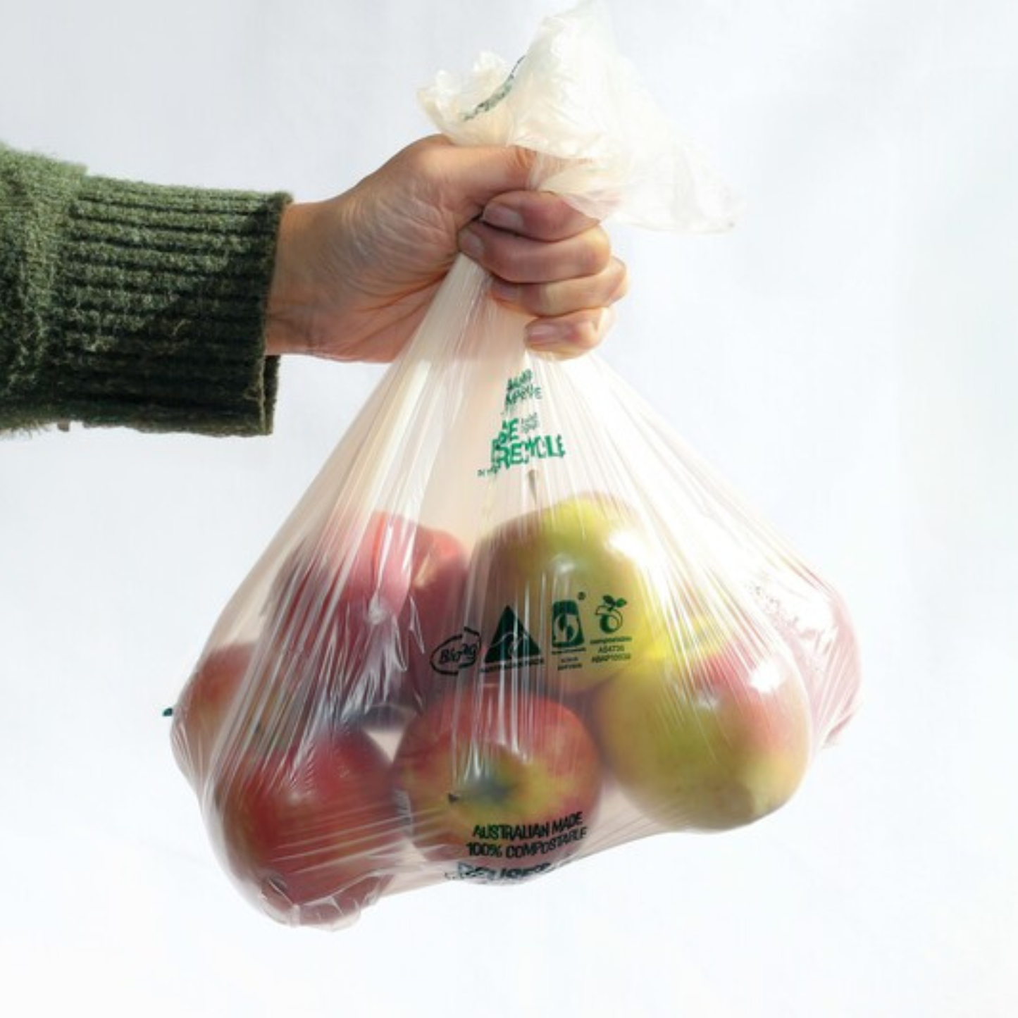 Hand holding a bag of apples in a BioBag compostable food produce bag