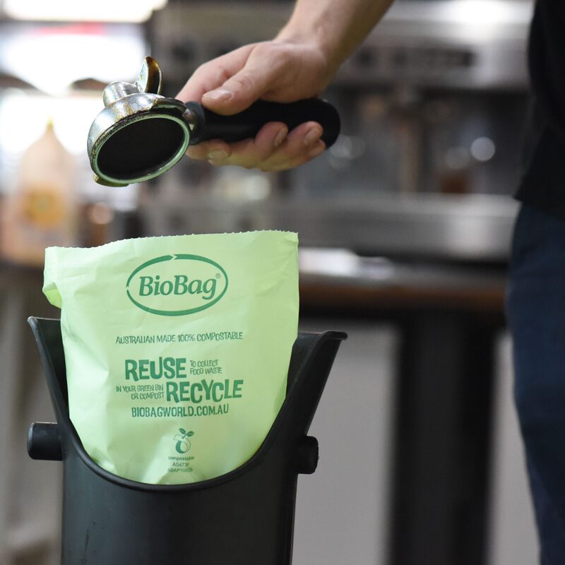 Person using a coffee group head with a BioBag coffee knock tube liner for waste