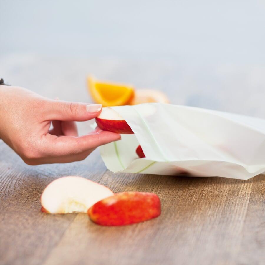 Person using a resealable compostable food storage bag for apple slices. 