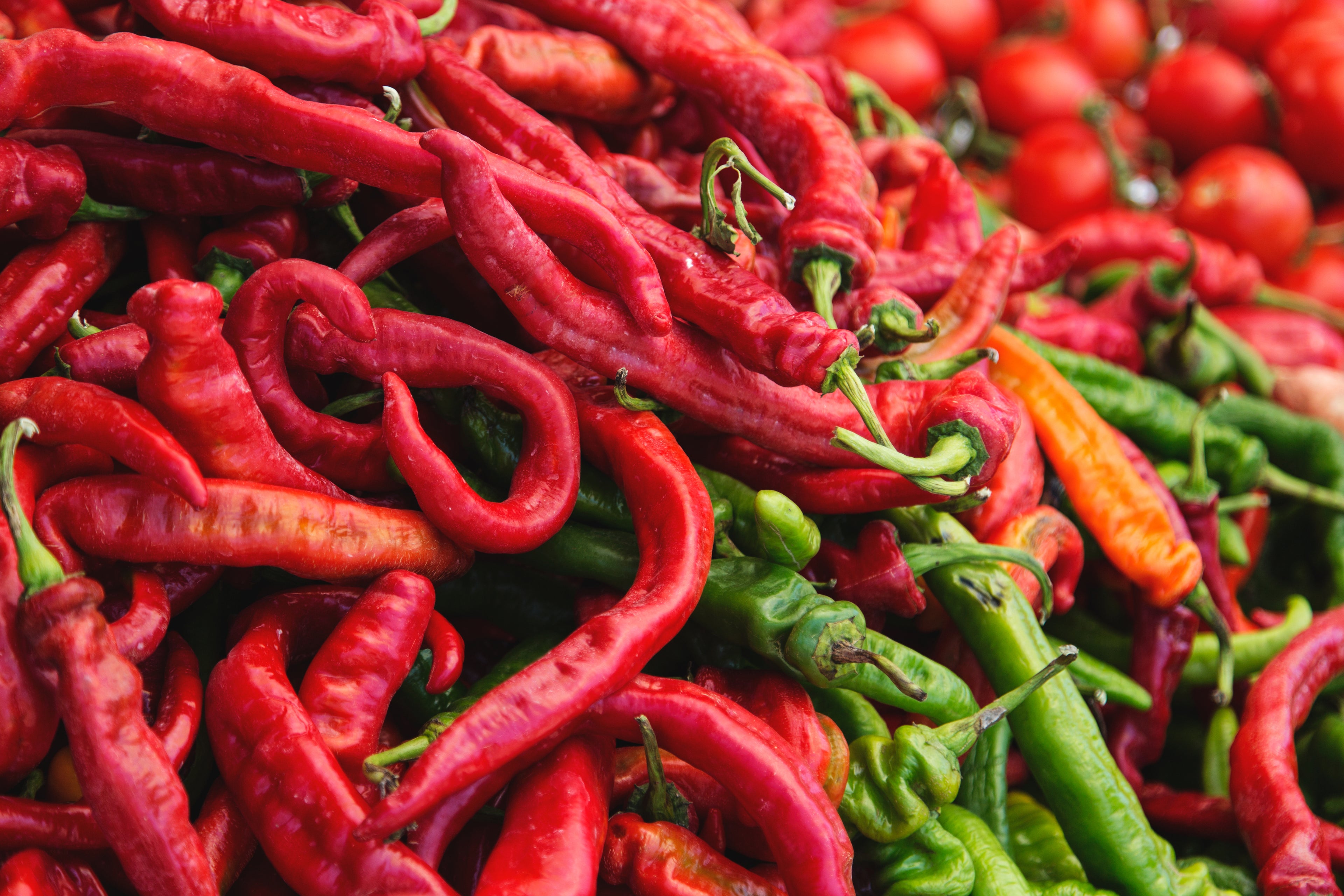 Close up photo of red and green chillis and cherry tomatoes - showing what can go in a compostable bin liner. 
